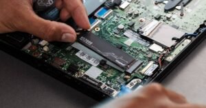 une main qui installe un disque dur SSD Kingston dans un pc portable