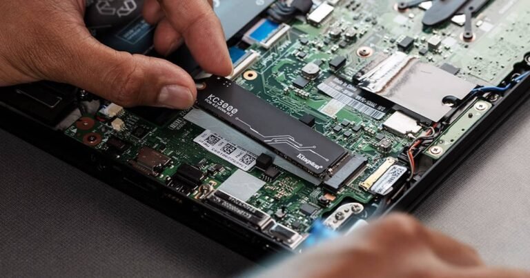 une main qui installe un disque dur SSD Kingston dans un pc portable