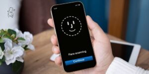 un smartphone dans la main d'un utilisateur. Sur l'écran du smartphone un visage souriant confirme le déverouillage par Face ID.
